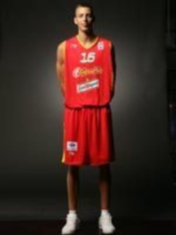 Jugador de baloncesto en uniforme rojo con el número 15, posando en un estudio con fondo oscuro.