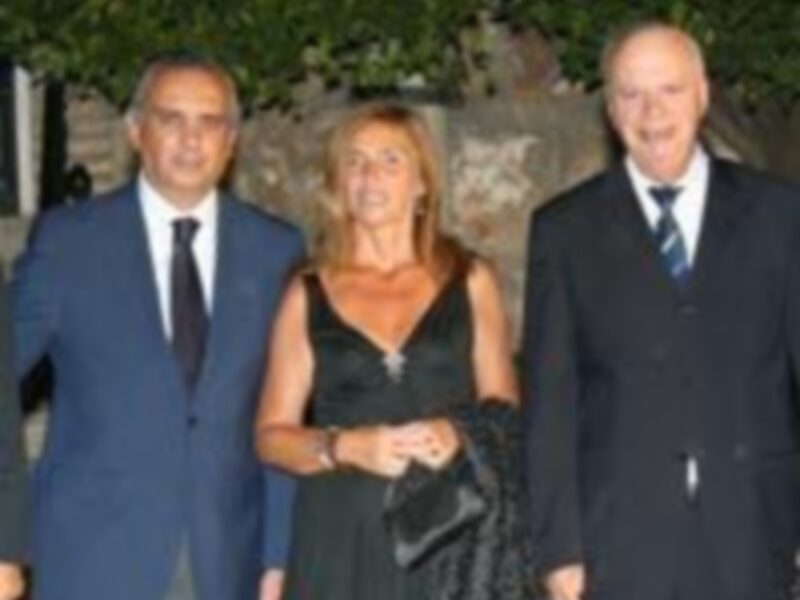 Dos hombres y una mujer posan juntos en una celebración formal, todos están vestidos de manera elegante.