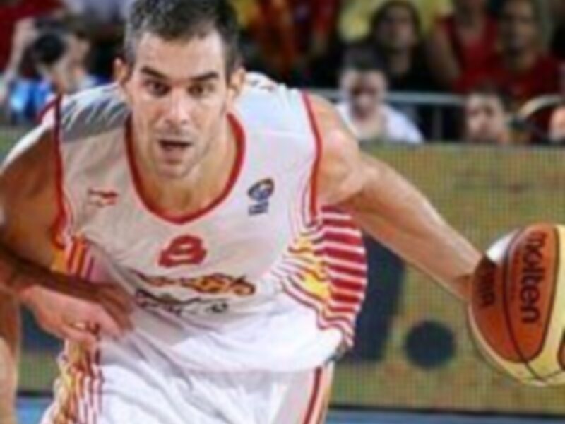 Un jugador de baloncesto en acción durante un partido, con el escudo de la selección española en su camiseta.