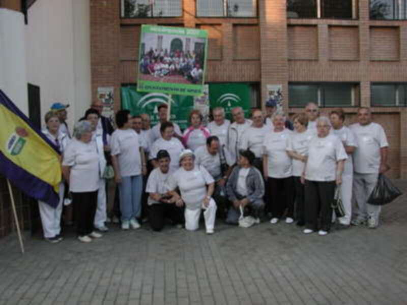 Un grupo de personas posando frente a un edificio con banderas y carteles de diferentes organizaciones sociales.