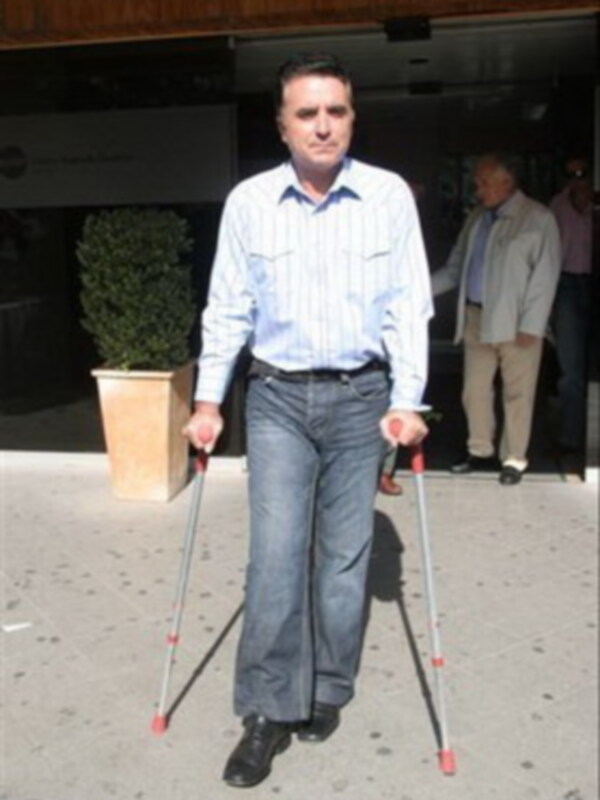 Hombre caminando con bastones en una calle urbana.