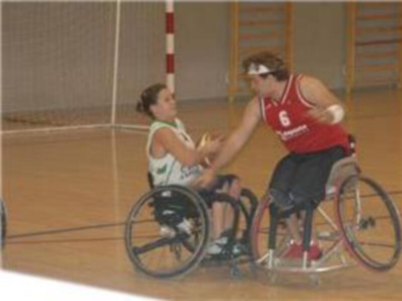 Jugadores de baloncesto en silla de ruedas en acción durante un partido en una cancha deportiva.