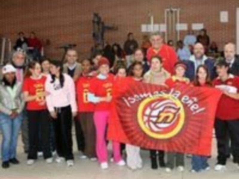 Equipo deportivo celebrando juntos con una bandera en un entorno deportivo.