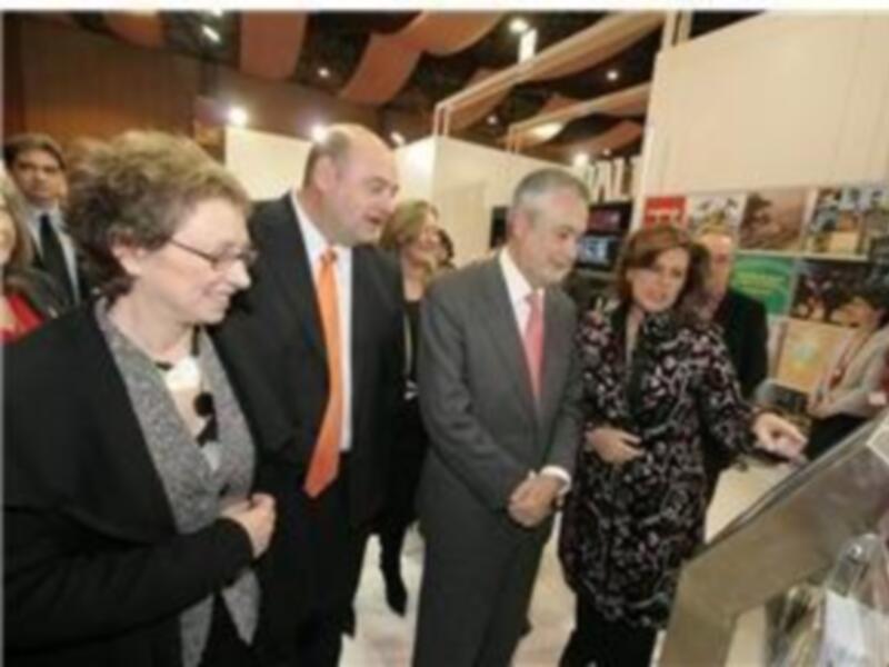 Persona en traje intercambian información con visitantes en un stand de exposición.