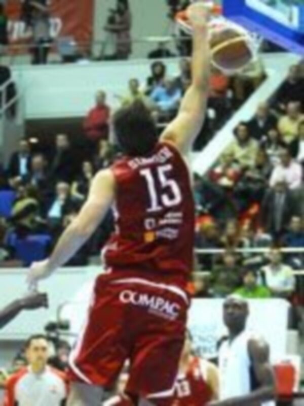 Jugador en acción durante un partido de baloncesto, lanzando el balón con intensidad.