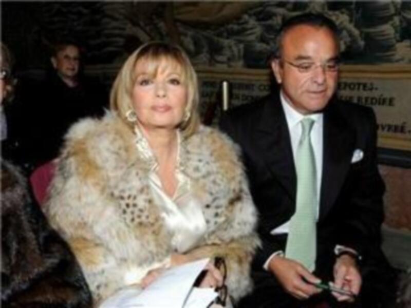 Una pareja elegante, con mujer en abrigo de piel y hombre en traje formal, posando juntos en un evento formal.