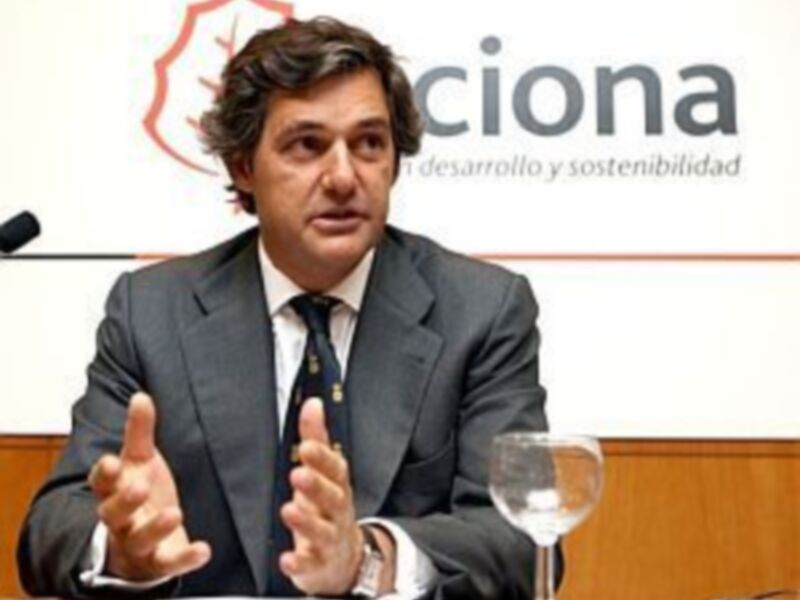 Hombre en traje hablando en una conferencia de prensa de Acciona, enfatizando puntos con las manos.