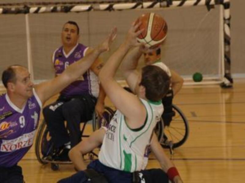 Un partido de baloncesto en silla de ruedas, con jugadores en acción en un gimnasio.