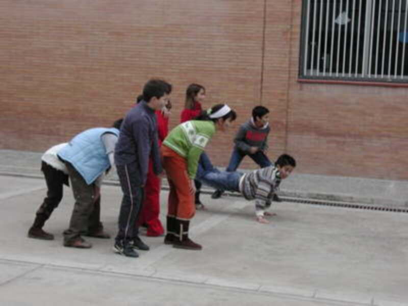 Un grupo de personas participa en una actividad de equilibrio al aire libre, apoyándose mutuamente.