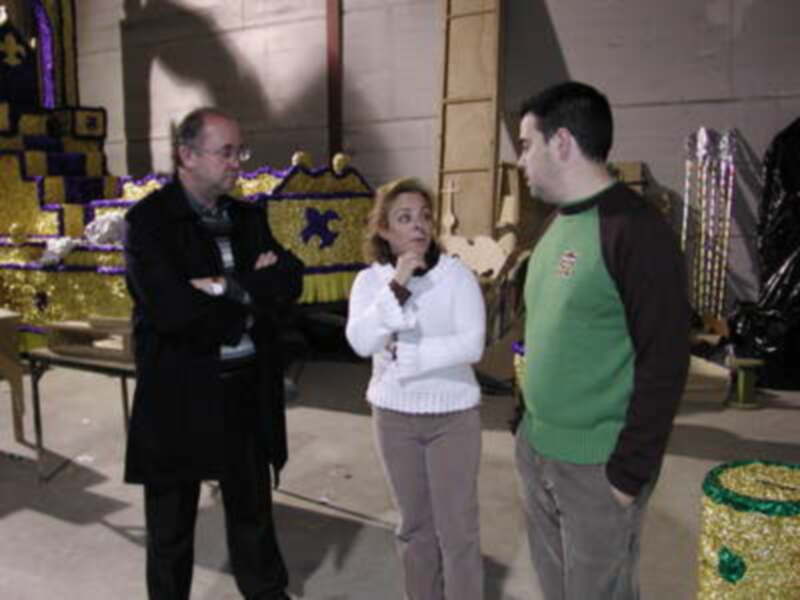 Personas discutiendo en un evento festivo con decoración de Mardi Gras.