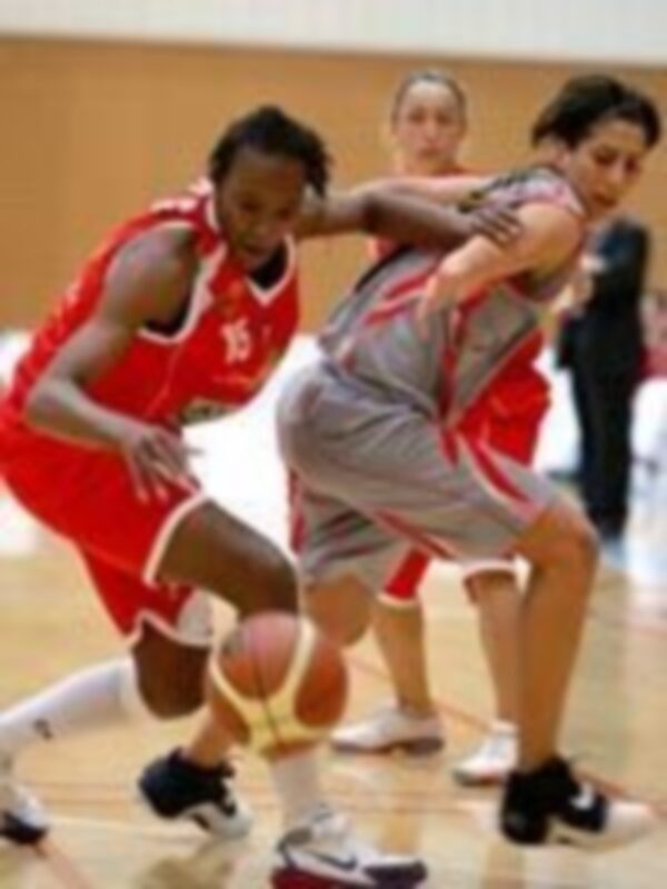 Jugadores de baloncesto en acción durante un partido, con un jugador en rojo y otro en gris, ambos con balones en la mano.