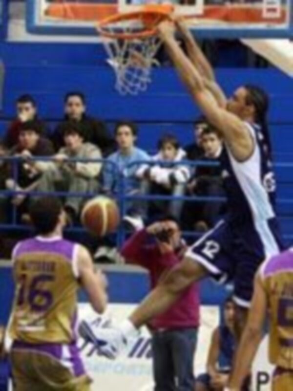 Jugador en acción durante un partido de baloncesto, realizando un mate en el aro.