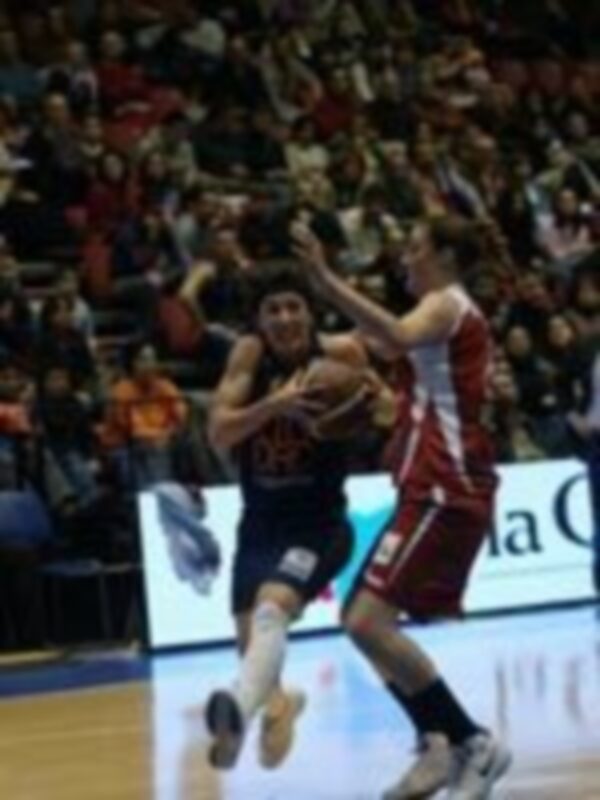 Jugador en acción durante un partido de baloncesto, driblando el balón en el centro de la cancha.