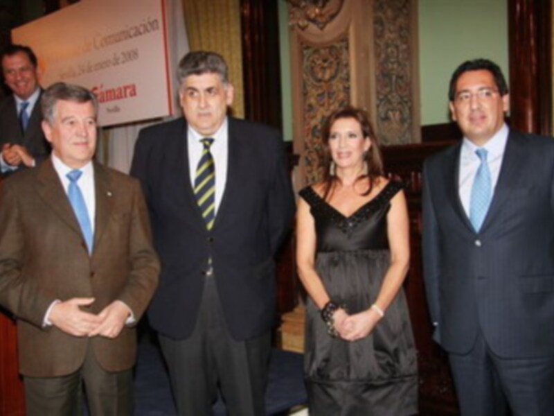 Una reunión formal en un entorno elegante, con cuatro personas vestidas de negocios, posiblemente en una conferencia o evento empresarial.