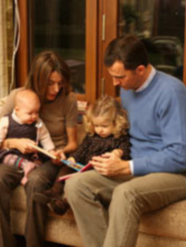 Familia disfrutando de un momento de lectura juntos en el sofá.