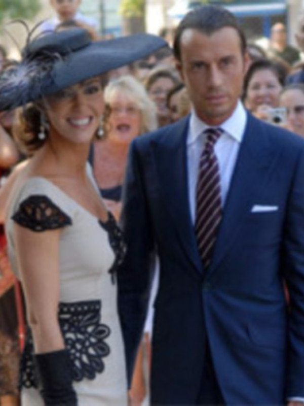 Una pareja elegante en traje y vestido formal, posando en una alfombra roja.