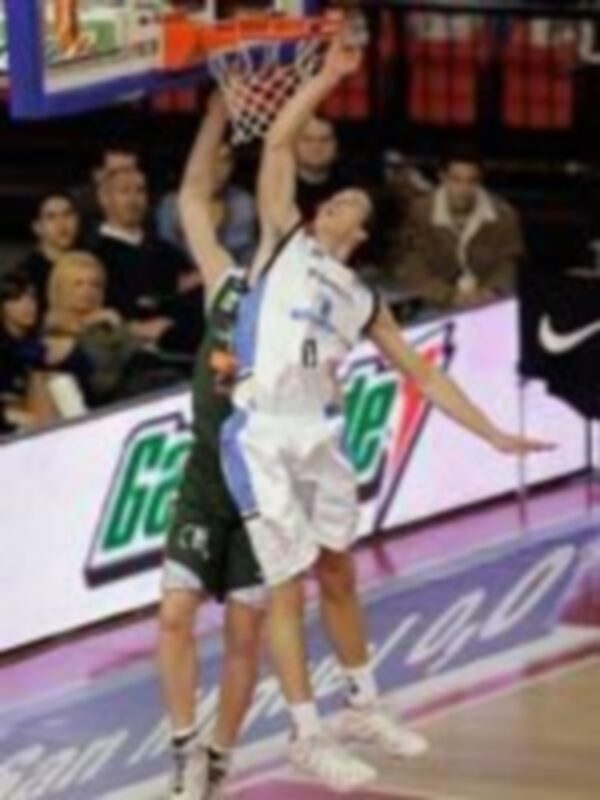 Jugador en acción durante un partido de baloncesto, realizando un mateso en el aro.
