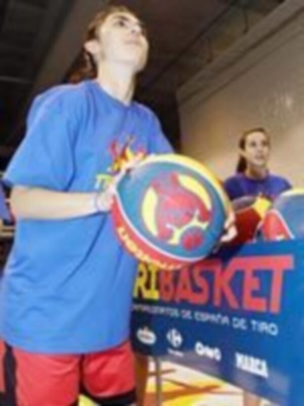 Joven jugando baloncesto con una pelota de entrenamiento en un entorno deportivo.