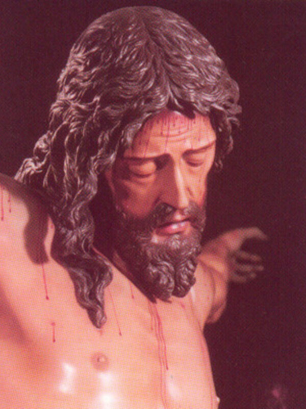 Estatua de Cristo crucificado con detalles en relieve y expresión serena.