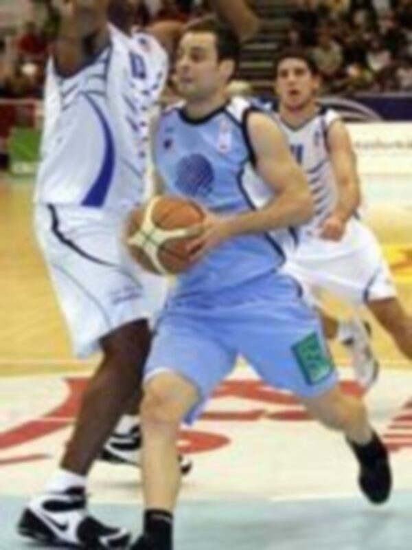 Jugador de baloncesto en acción durante un partido, controlando el balón con el uniforme azul.