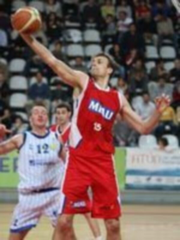 Jugador en acción durante un partido de baloncesto, lanzando el balón con determinación.