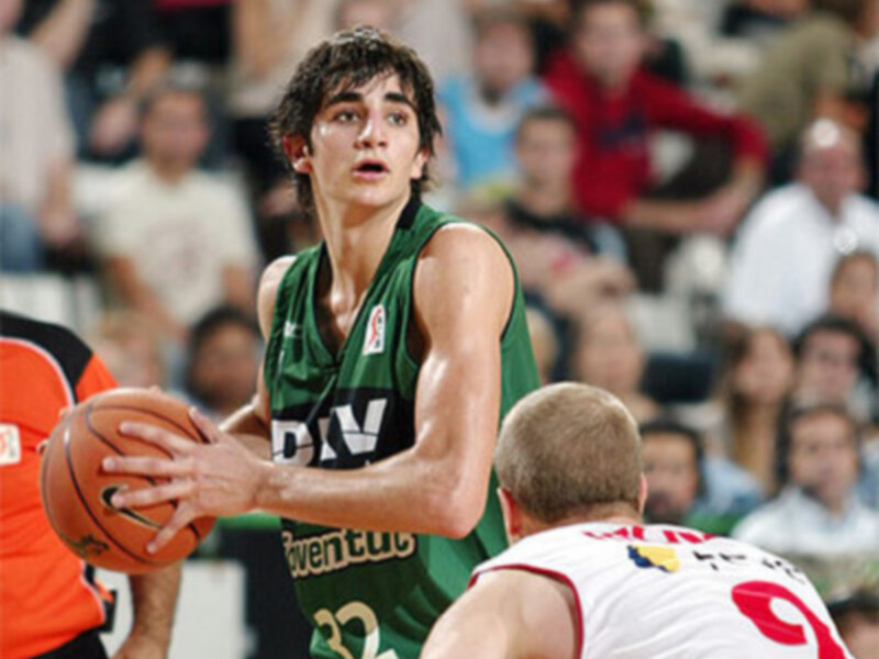 Jugador de baloncesto en acción durante un partido, vestido con una camiseta verde y número 32, en un entorno de público atento.
