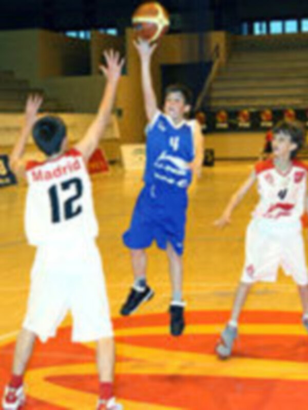 Jugador en acción durante un partido de baloncesto, lanzando el balón con intensidad en el aro.