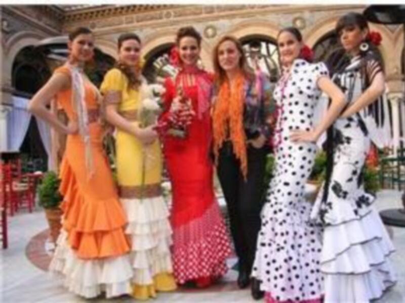 Un grupo de mujeres vestidas con trajes de flamenca posan para una foto en un evento cultural.