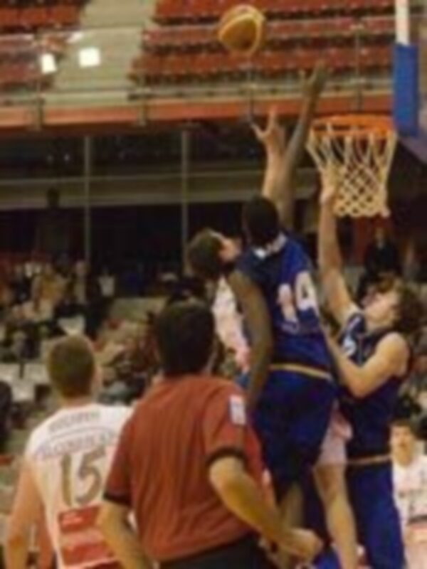 Un jugador de baloncesto en acción durante un partido en un estadio lleno de espectadores.