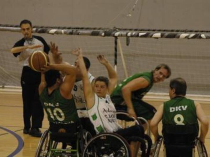 Jugadores de baloncesto en silla de ruedas en acción durante un partido. DKV y Alcobendas competen en un entorno deportivo.