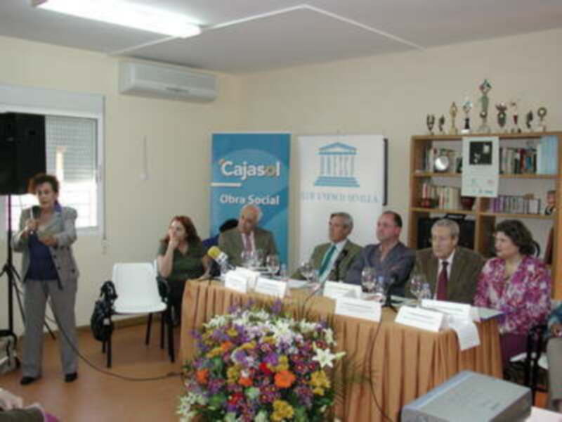 Reunión de trabajo en un espacio bien iluminado con participantes en una mesa y un panel de representantes de Cajasol.