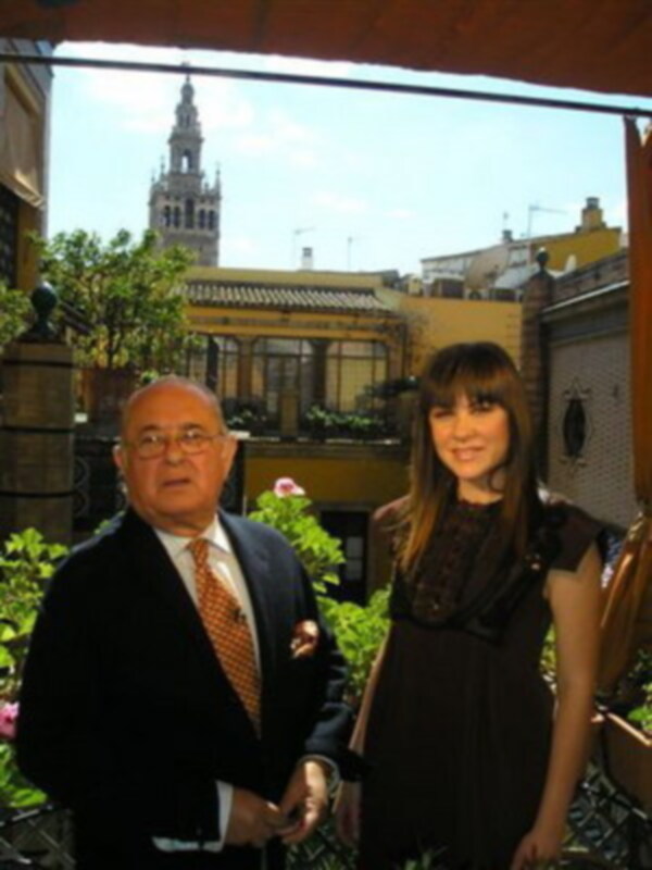 Dos personas posan juntas en un patio con vistas a la Giralda de Sevilla, España.