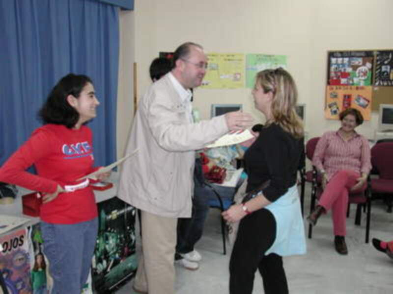 Un grupo de personas intercambia un documento en un ambiente educativo o de oficina, rodeado de juguetes y materiales escolares.
