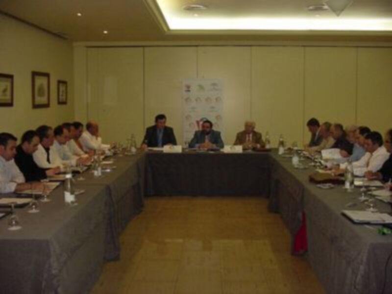 Reunión de trabajo en una sala de conferencias con participantes sentados alrededor de una larga mesa.