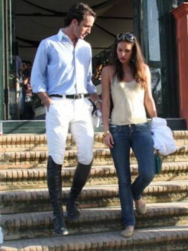 Una pareja camina por una escalera, ella viste jeans y una camiseta, él lleva pantalones blancos y botas negras.