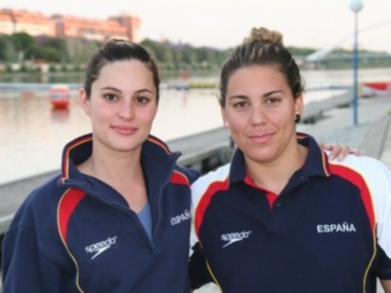 Dos personas en ropa deportiva de Speedo, con el texto 'España' en la camiseta de la derecha, posando frente a un río.