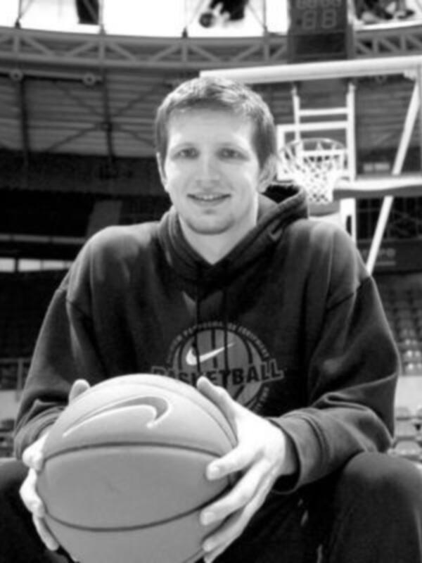 Un hombre sosteniendo un balón de baloncesto en una cancha de baloncesto.