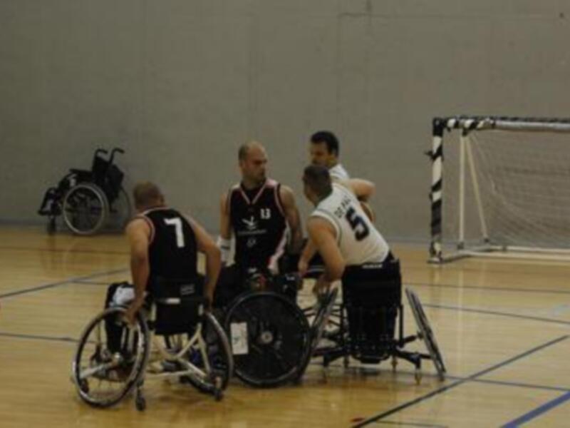 Jugadores en sillas de ruedas durante un partido de baloncesto en una cancha de baloncesto.