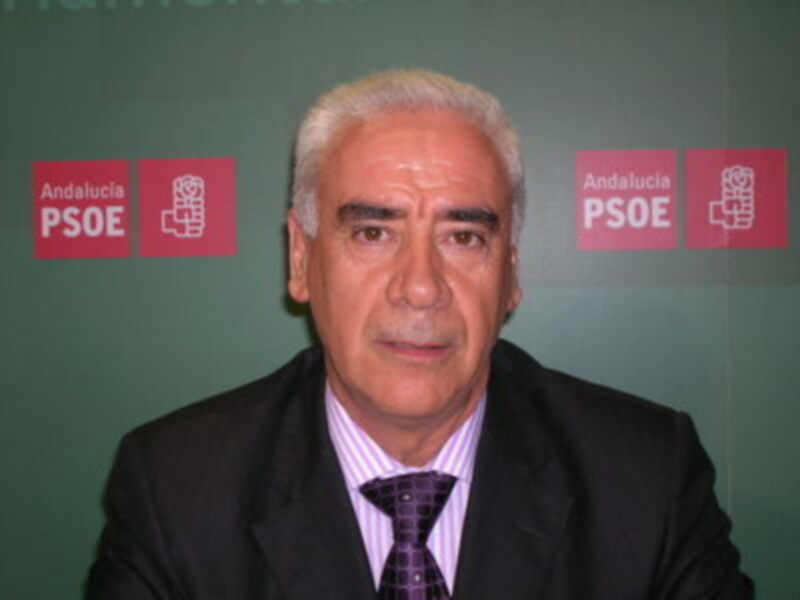 Persona en traje y corbata frente a fondo verde con logos del PSOE y Andalucía.