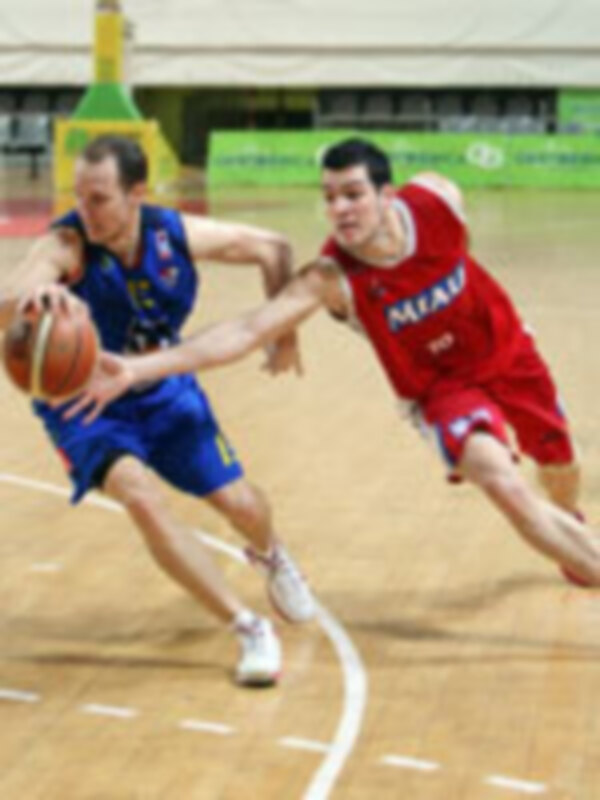 Dos jugadores de baloncesto en acción durante un partido, uno con camiseta roja y otro con camiseta azul.