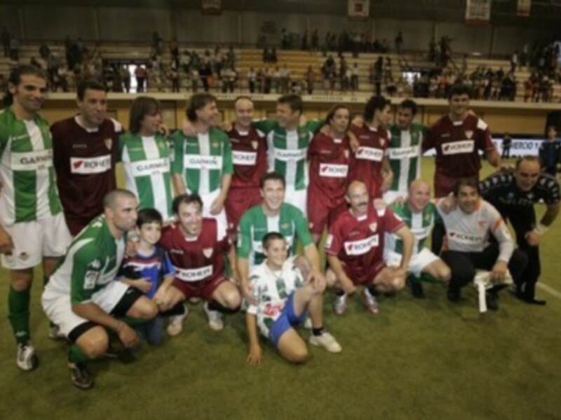 Equipo de fútbol posando en el campo, con camisetas verdes y rojas.