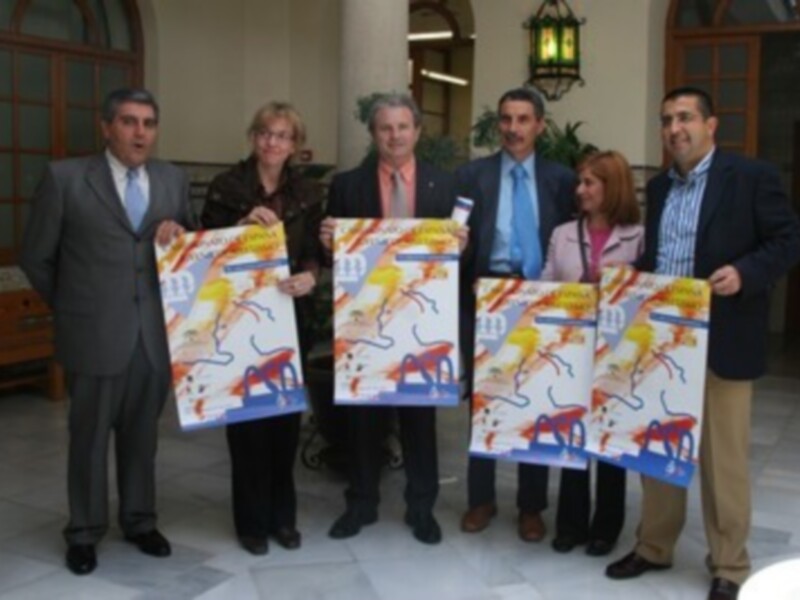 Un grupo de personas posa con carteles de arte abstracto en un ambiente formal.