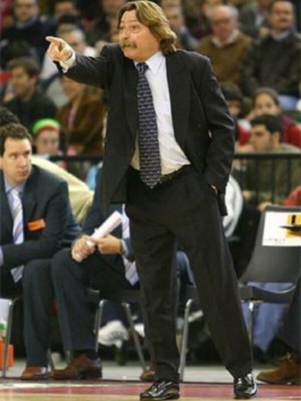 Entrenador en acción durante un partido de baloncesto, dirigiendo con gestos y papel en mano.