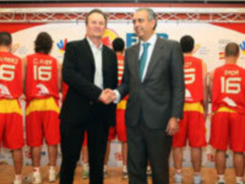 El entrenador de un equipo de baloncesto estrecha la mano de un ejecutivo durante una conferencia de prensa en el estadio.