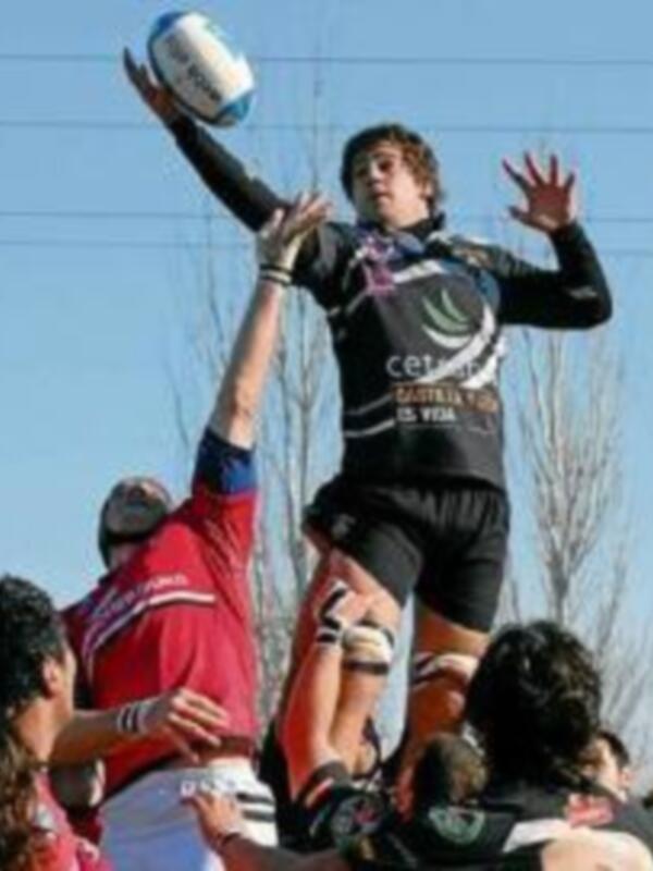 Un jugador de rugby levantando el balón en un juego de alto nivel, con otros jugadores en el fondo. El equipo lleva camisetas con el nombre 'Cordoba'.