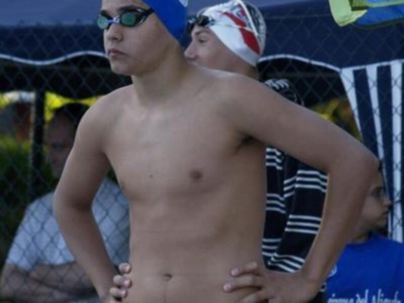 Atleta de natación listo para competir, con gorro y gafas de natación, en un entorno deportivo.
