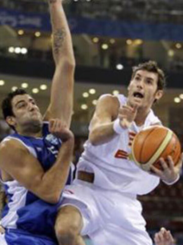 Jugadores de baloncesto en acción durante un partido en un estadio iluminado.