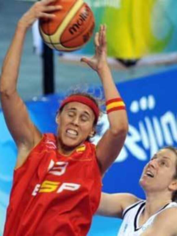 Una jugadora de baloncesto en acción, con el logo de la competición en el fondo.