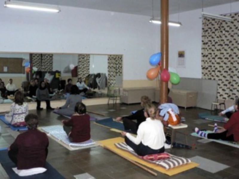 Clase de yoga para niños en un ambiente acogedor con colchonetas y globos decorativos.