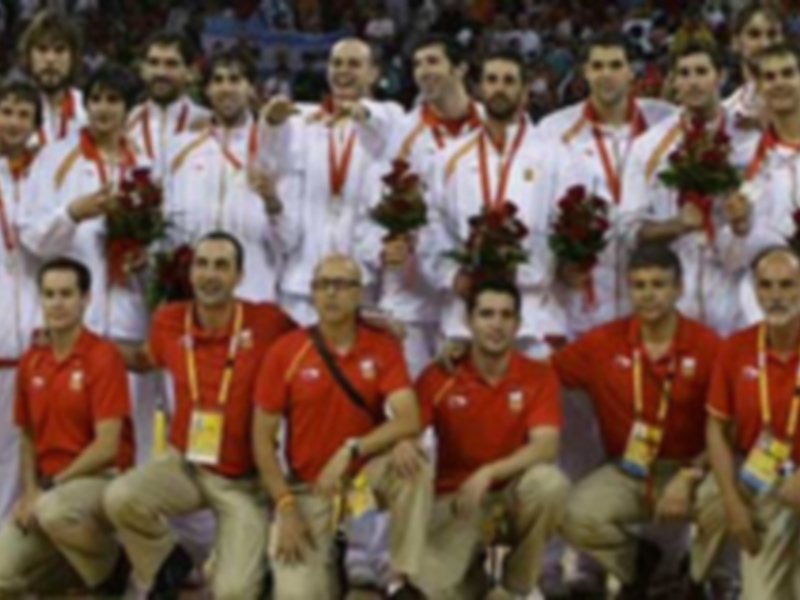 Equipo español de baloncesto celebrando su victoria en un torneo internacional, todos con camisetas rojas y medallas al cuello.